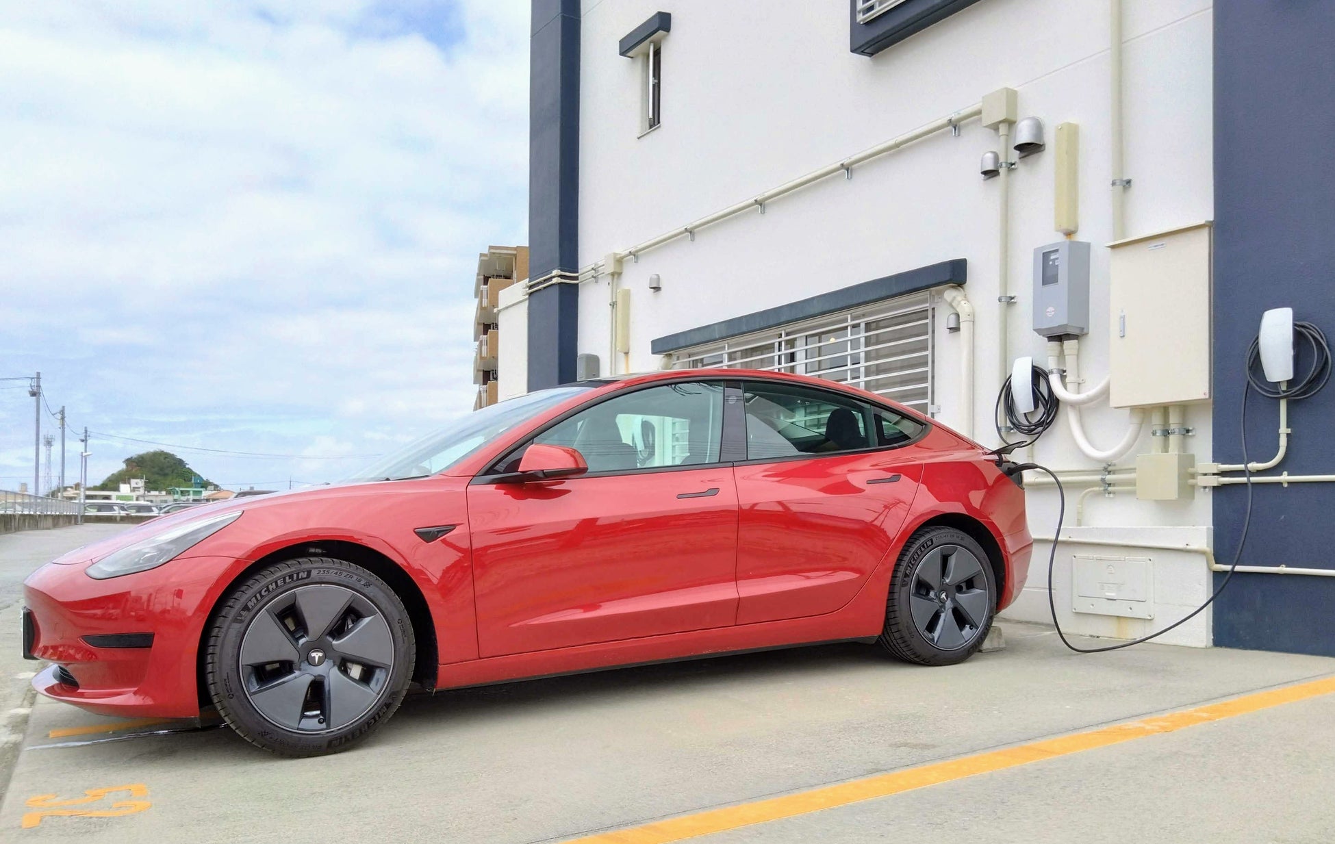 Teslaモデル3と、多数の充電設備を備える営業所