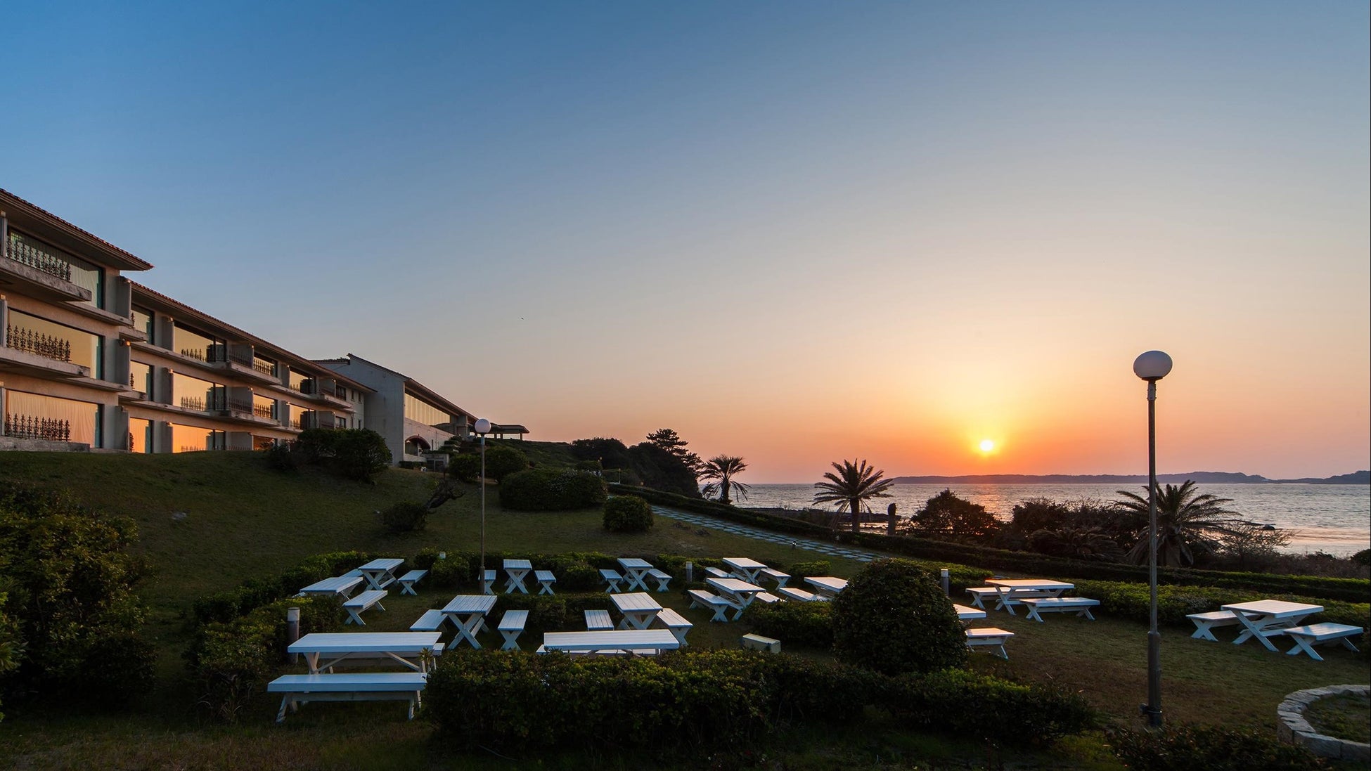 海に沈む夕日とホテルガーデン