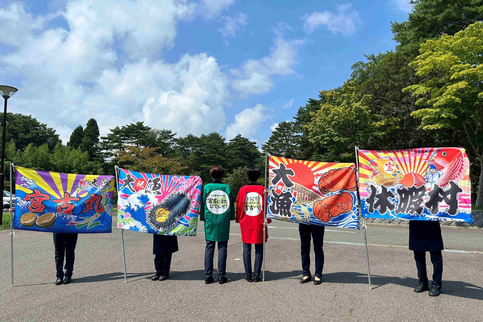 「ようこそ！」と「お気をつけて！」の気持ちを込めて、縁起物の大漁旗を振っています