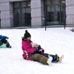 休暇村嬬恋鹿沢、ホテル前の雪遊び広場でソリを楽しむファミリー