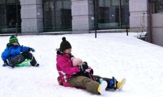 休暇村嬬恋鹿沢、ホテル前の雪遊び広場でソリを楽しむファミリー