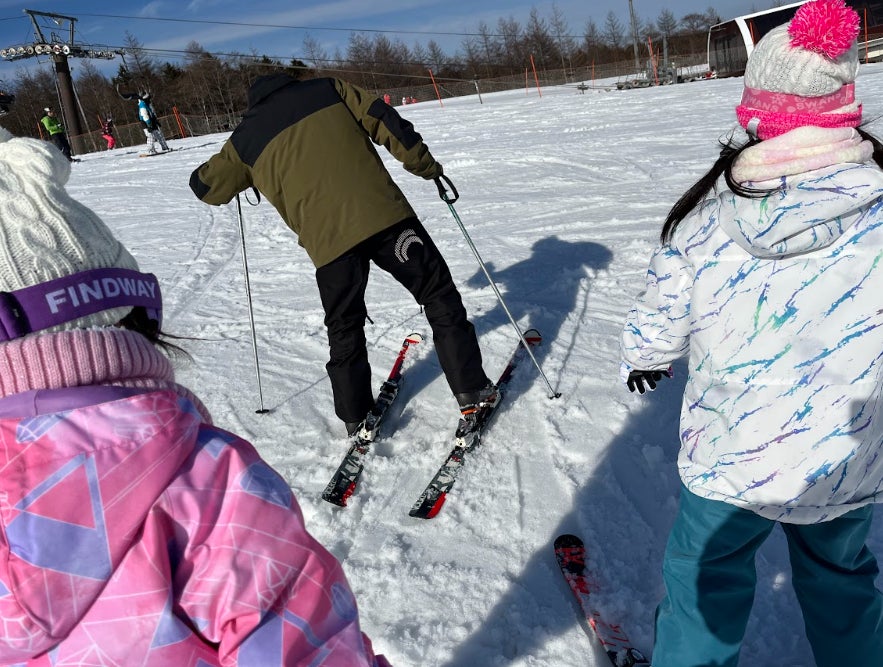 「あおぞらスキー体験」参加中の子ども（両脇2名）が、BUBクルーに教えてもらう様子